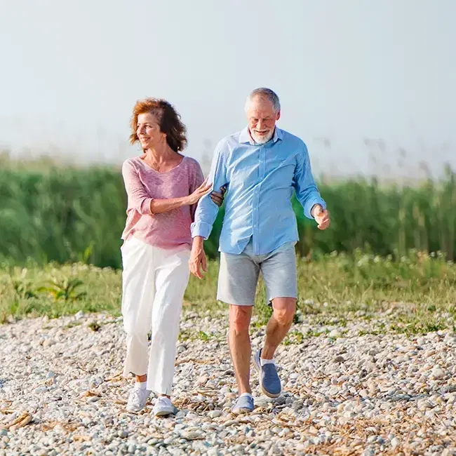 Happy retired couple walking on the beach