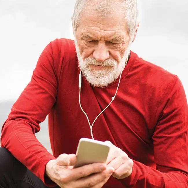 Retiree outside using mobile phone to hear music
